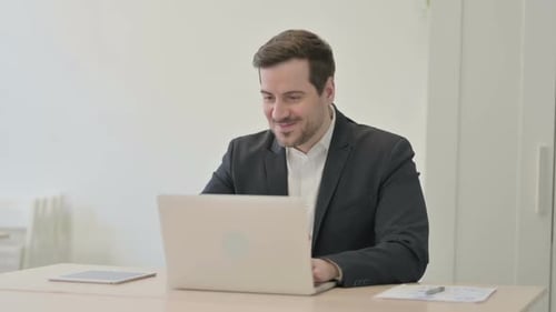 Businessman Celebrating Online Success on Laptop in Office
