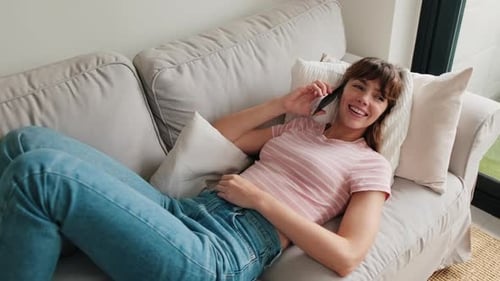 Smiling Woman Lying on Sofa Talking on Phone