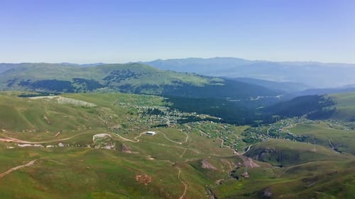 Aerial view of village among green meadows and mountains in summer Georgia