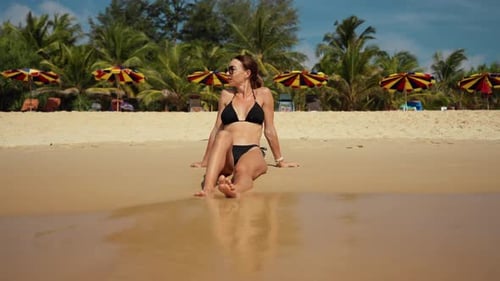 Blonde Woman in Black Bikini Sitting on Ocean Beach in Tropical Paradise Island with Turquoise Water
