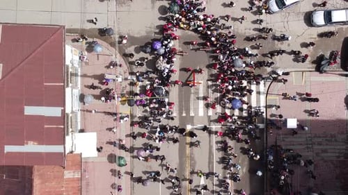 A drone shot of a crowded street following a man portraying Jesus Christ while carrying a cross