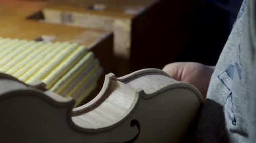 close up of artisan luthier maker work on new classic handmade raw violin smooth edge in waist and p