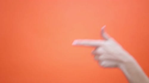 Die Frau hebt ihren Daumen auf einem isolierten roten Hintergrund und zeigt dann mit dem Zeigefinger darauf
