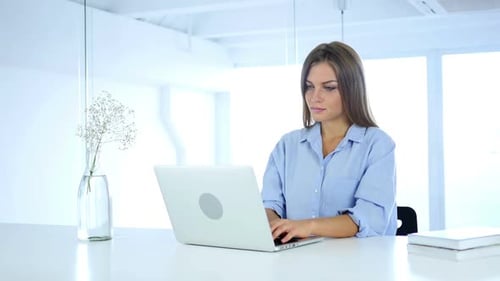 Serious Woman Working On Laptop in Office