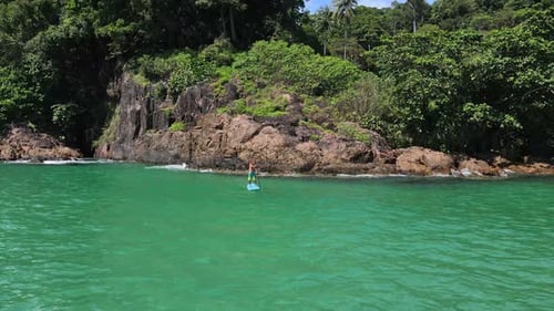 low angle Aerial drone bird's eye view of man exercising on a sup paddle board in turquoise tropical