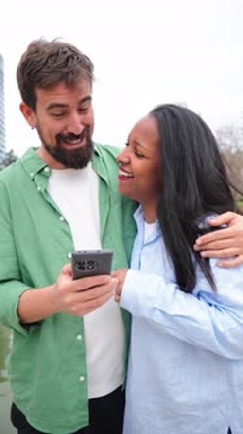 Smiling Couple Looking at Phone Together in Urban Setting
