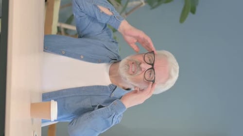 Gray-Haired Man Experiencing a Terrible Headache at Table