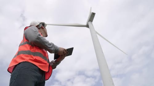 Progressive Engineer Working with the Wind Turbine with the Sky As Background