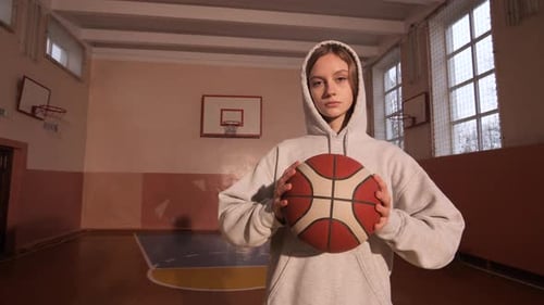 Young Female Basketball Player Holding Ball in School Gym
