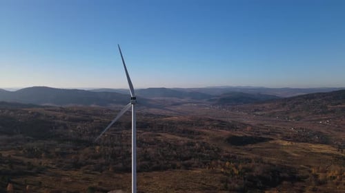 Aerial Panoramic View of a Wind Turbine with Rotating Blades Against Autumn Landscape