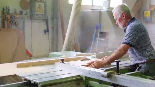 Senior Carpenter Cutting Wood on Sliding Table Saw