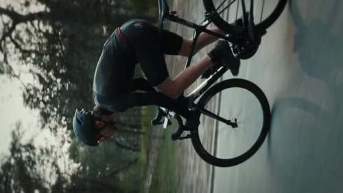 Pro male cyclist riding road bicycle, sprinting out of saddle. Vertical video