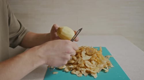 Man Continues Peeling Potato Over Large Pile of Peels