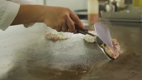 Chef Cooking And Turning MEat On Other Side Using Spatula On Hot Griddle. - close up