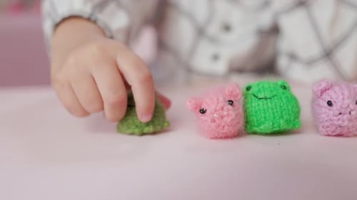 Child Playing with Yarn Toys on Pink Table