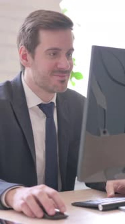 Excited Businessman Works at Computer in Office