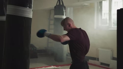 Boxer Punches Heavy Bag Exercising in Sports Gym