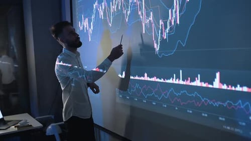 Young Adult Man Analyzing Financial Charts on Screen