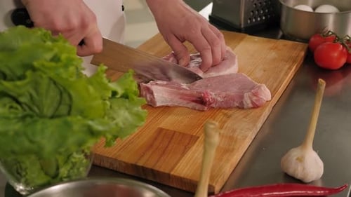 Chef Cutting Raw Meat in Kitchen