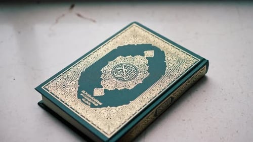 Der Heilige Koran der islamischen Religion liegt geschlossen vor Beginn des Gebets auf dem Tisch eines Muslims.
