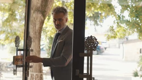 Mature Businessman Entering Hotel with Luggage. Man Opening the Hotel Front Door.