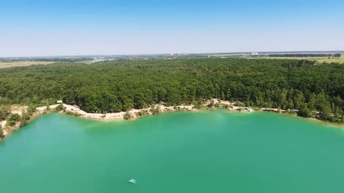 Deep blue lake with white sandy banks around. Green forest covering the waterfront.