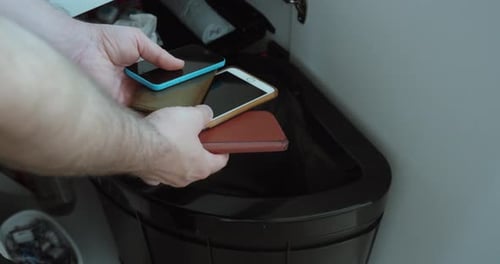 Throwing Old Smartphones into Trash Bin for Electronic Waste Disposal