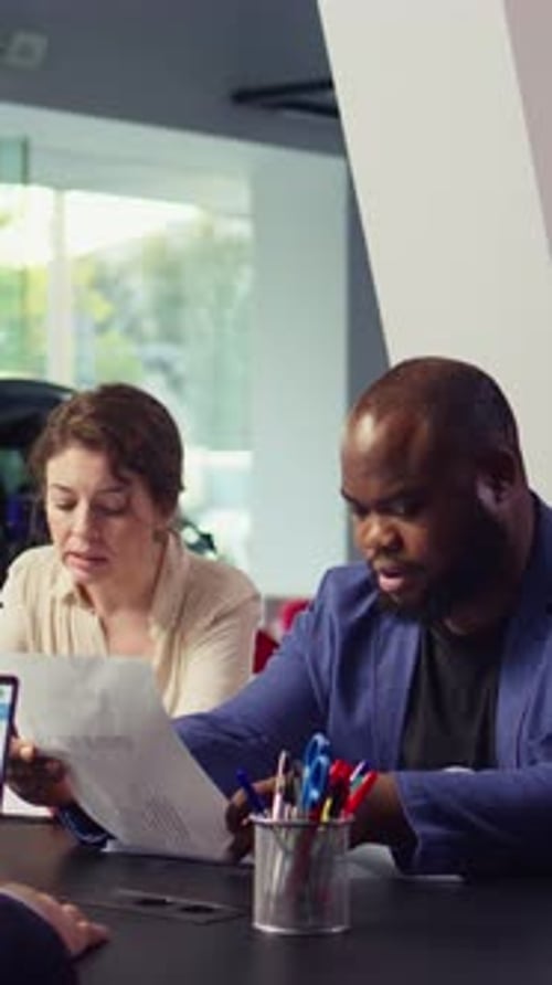 Vertical Video Customers in Dealership Completing Necessary Car Payment Paperwork