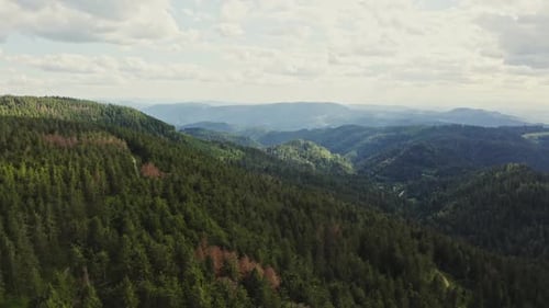 Aerial View of Forested Mountains with Cloudy Blue Sky