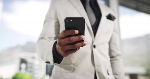 4k video footage of an unrecognizable businessman using his cellphone while standing in the office