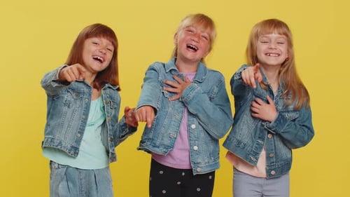 Laughing Children Pointing at Camera, Yellow Background