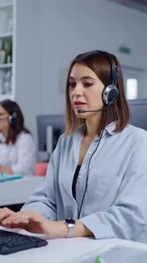 Focused Female Call Center Operator Working with Headset and Computer in Modern Customer Support