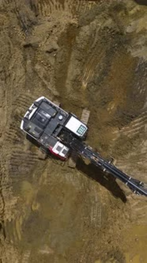 Aerial View of Excavator Digging in Muddy Field