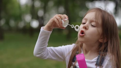Girl Blowing Bubbles in Grassy Area