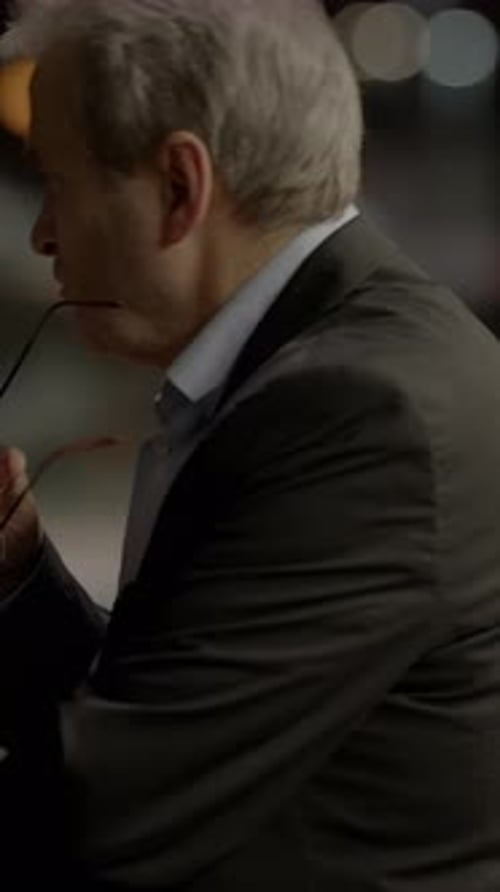 Man Holding Glasses in City at Night