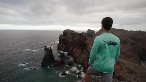 A man gazes at the dramatic coastline and sharp cliffs of Ponta de São Lourenço in Madeira, Portugal