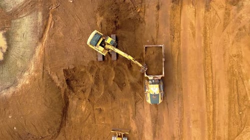 Top-Down View of Excavator Loading Dump Trucks for Grading Dirt at Construction Site