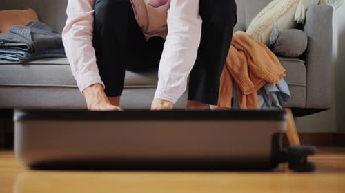 Person Packing Suitcase for a Trip on Sofa