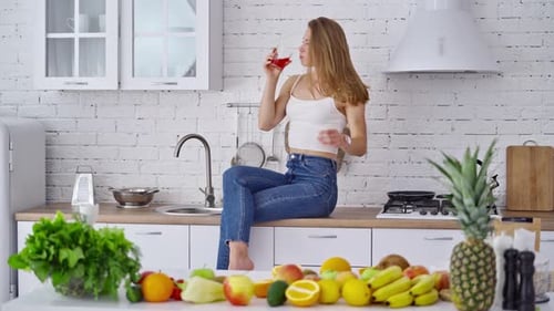 Woman Enjoys Refreshing Drink in Bright Kitchen