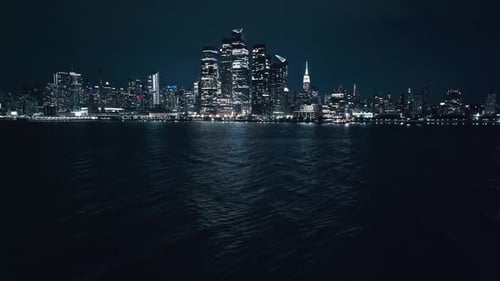 New York City skyline of iconic buildings at night across East River, aerial establishing view