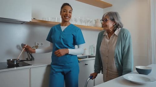 Friendly Caregiver With Senior Woman in Kitchen