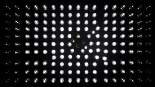 Nahaufnahme eines leuchtenden LED-Gitters mit farbigen Lichtern auf dunklem Hintergrund.