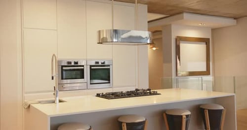 Modern kitchen with island, bar stools, and stainless steel appliances in home