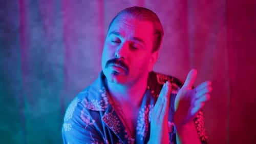 An Enthusiastic Man is Clapping Joyfully in a Beautiful Colorful Studio Lighting Environment