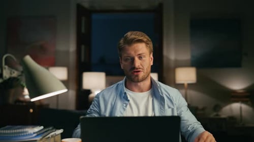 Homme concentré parlant à l'ordinateur dans une maison confortable. Un gars sérieux résolvant des tâches sur un ordinateur portable. Indépendant occupé...