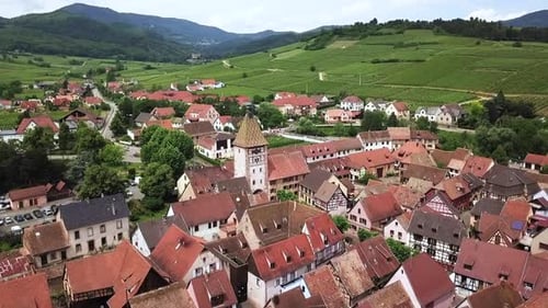 Aerial drone shot towards ancient church bell tower in Bergheim, France.