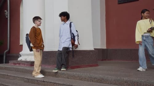 Two Young Girls Waving Goodbye to their Classmates, Going Home After School