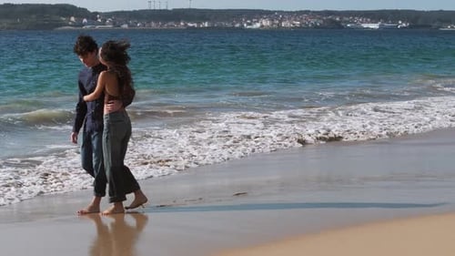 In love Young Couple Embracing, Holding Hands And Walking At The Beach In Summer. - aerial shot