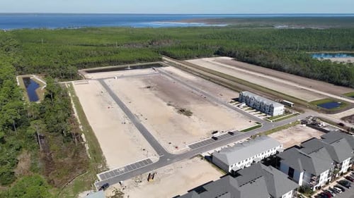 An Aerial View of Cleared Land Plots, Retention Ponds, and Residential Buildings Surrounded by Dense