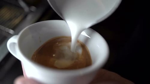 Milk Pouring into Espresso Coffee Close Up